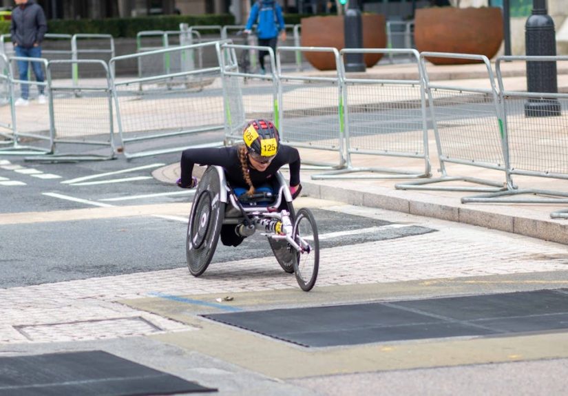 A dedicated athlete competes in a marathon using a racing wheelchair on city streets.