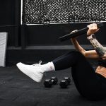 A determined woman performs a core workout in an indoor gym setting.