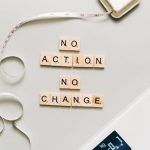 Motivational concept with scrabble tiles spelling no action no change alongside a measuring tape and scale.